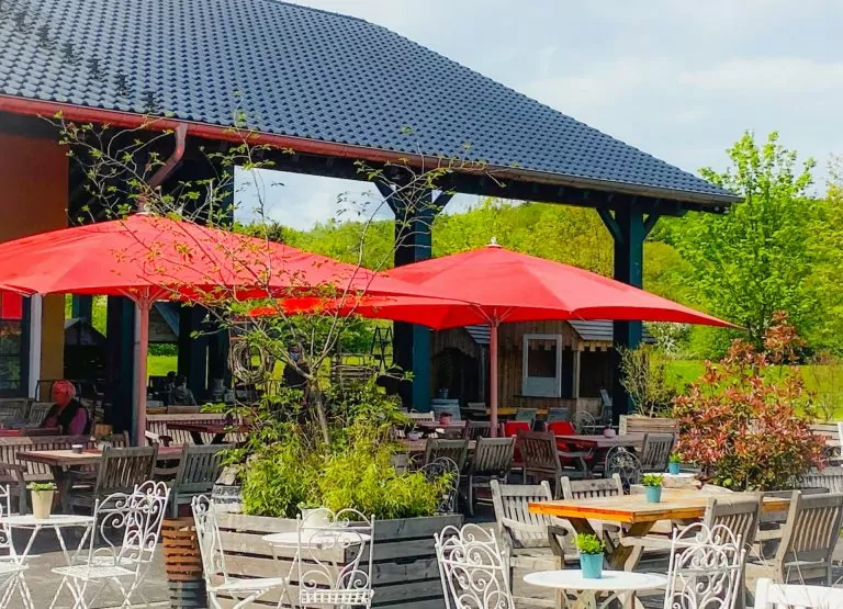 Hof-Restaurant mit roten Schirmen und vielen gemütlichen Sitzgelegenheiten.